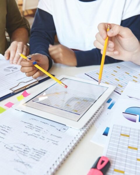 Syria Feasibility Study: A diverse group of people analyzing charts and data on a tablet and papers, with pencils and sticky notes scattered on a table.